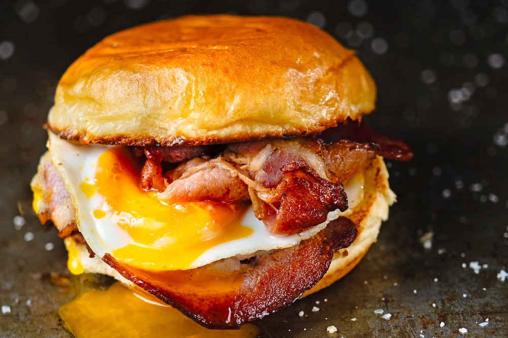 close up of rustic bacon egg breakfast sandwich bun